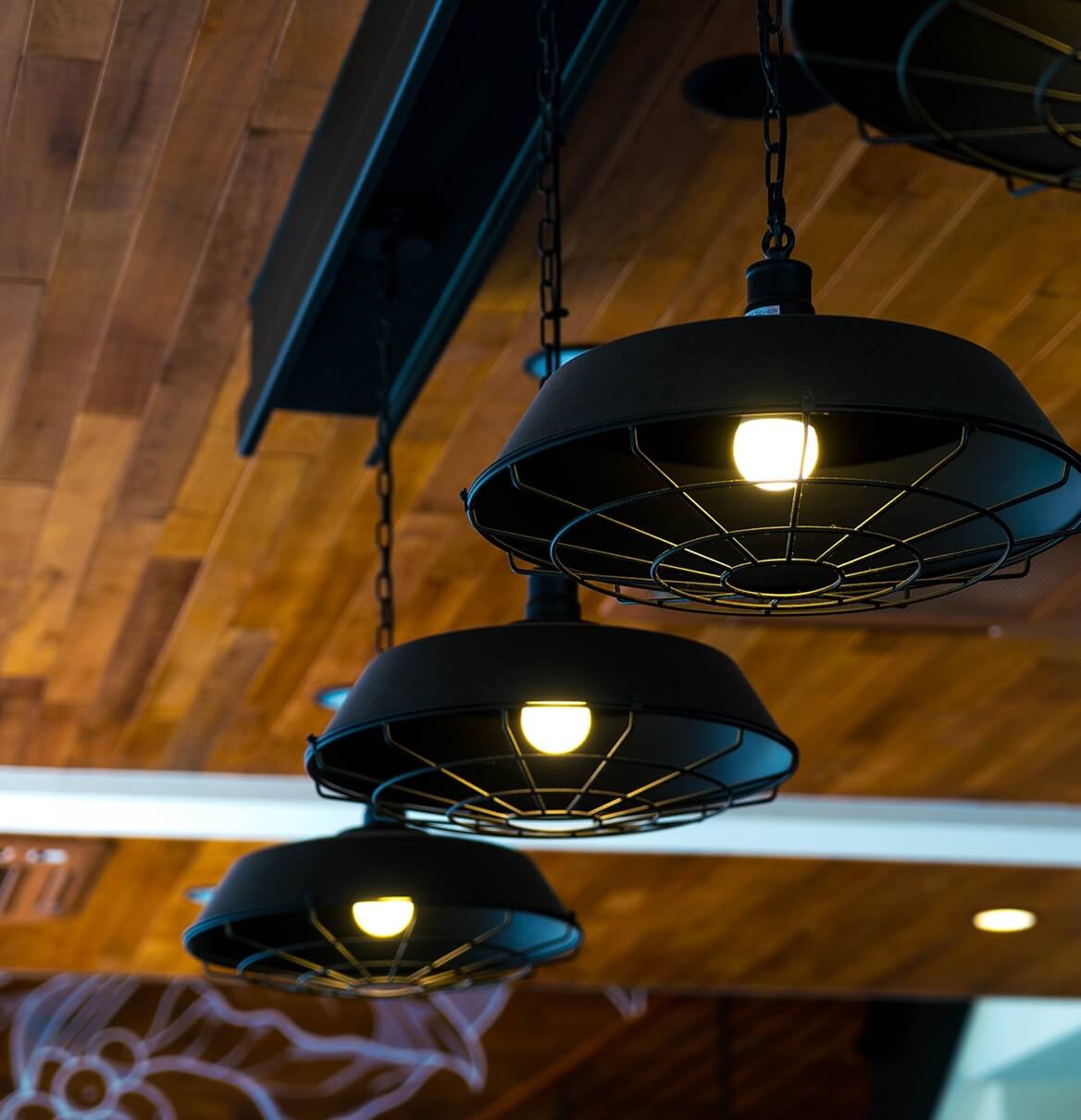 Drei Industrie-Pendelleuchten im Retro-Stil mit LED-Birnen an Holzdecke
