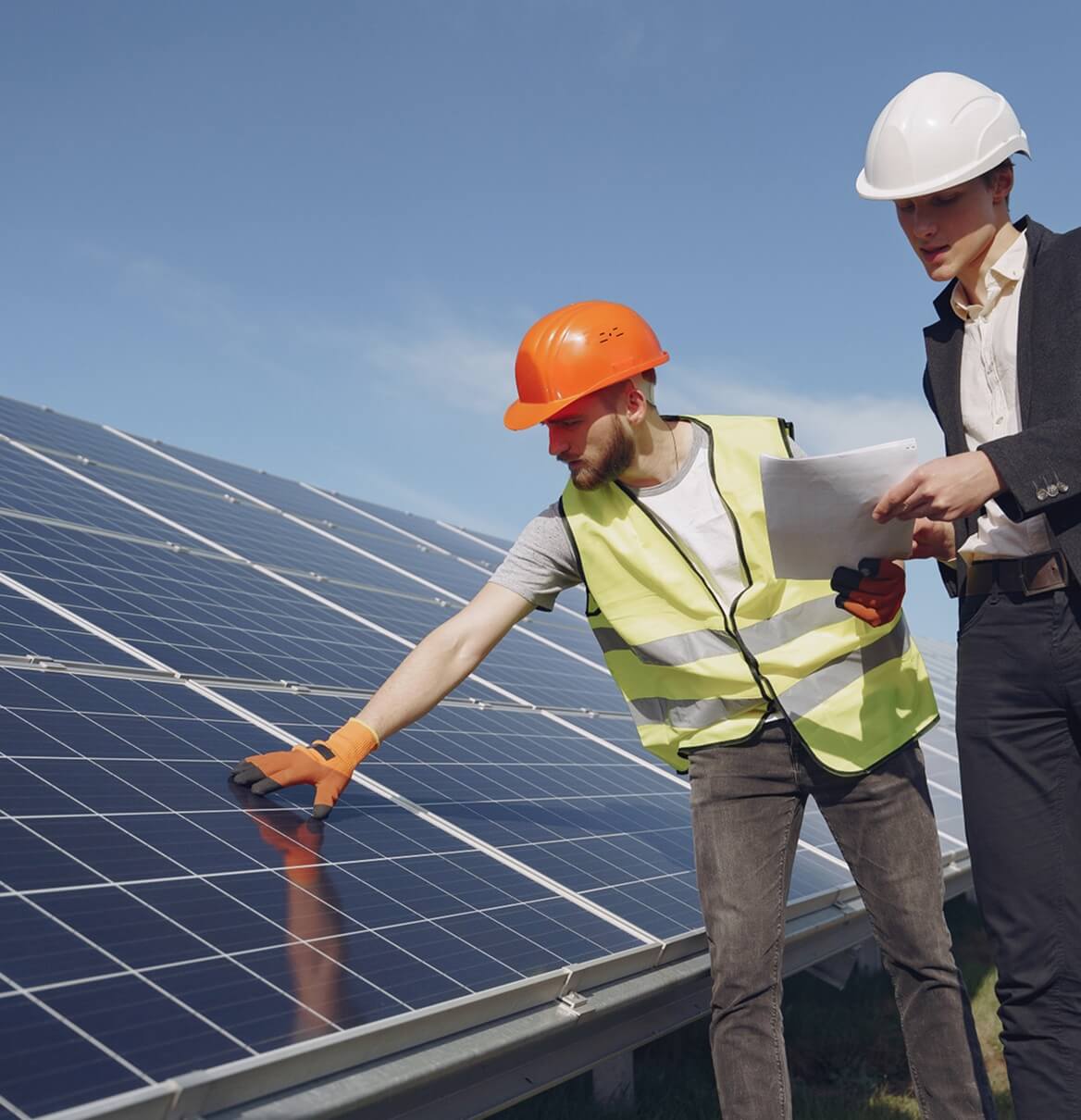 Zwei Techniker prüfen gemeinsam Photovoltaikmodule mit Unterlagen bei Inspektion